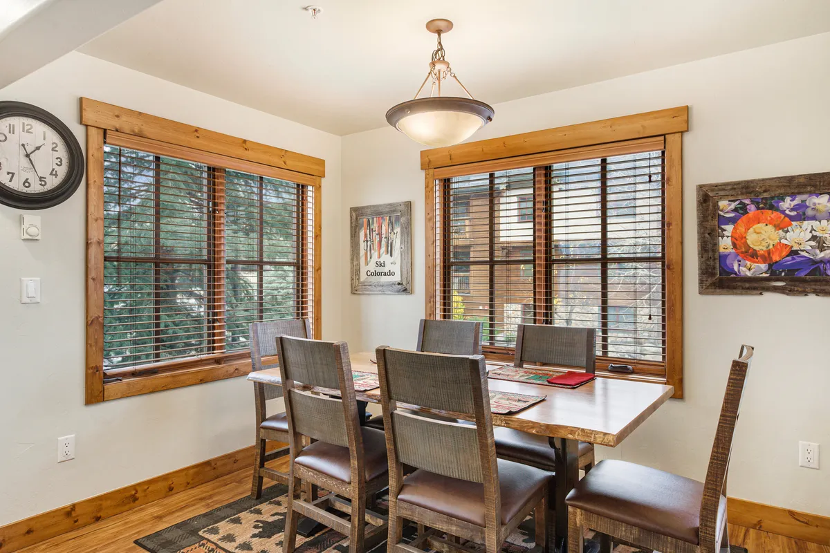 A spacious dining area is featured, centered around a large wooden dining table with window views and warm wall art. The ambiance is welcoming, ideal for family meals, game nights, and making memories.